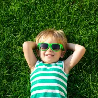 kid laying in grass with sunglasses