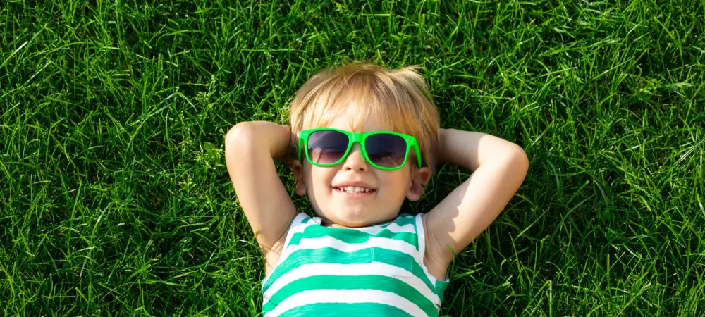 kid laying in grass with sunglasses